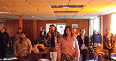 Asistentes al taller de autorregulación emocional de pie con los ojos cerrados en un ejercicio de meditación.