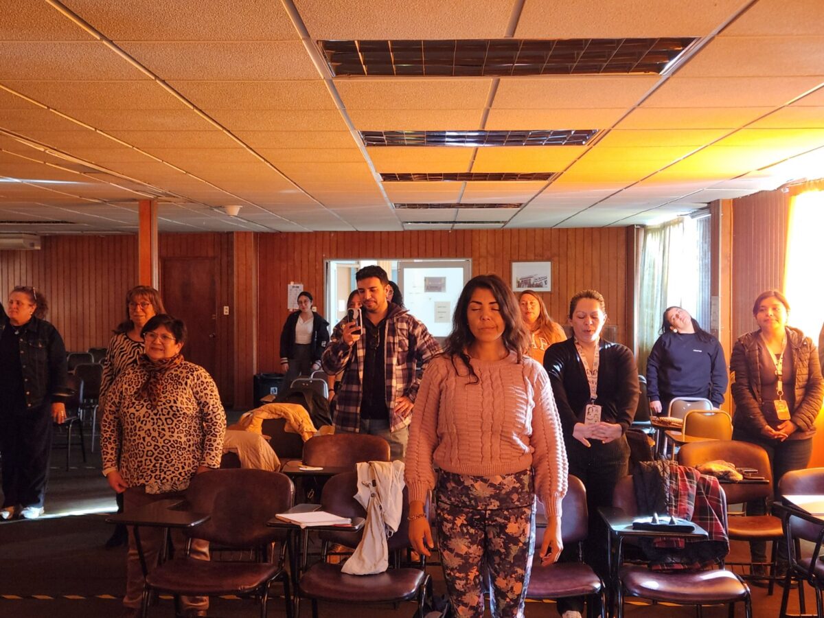 Asistentes al taller de autorregulación emocional de pie con los ojos cerrados en un ejercicio de meditación.
