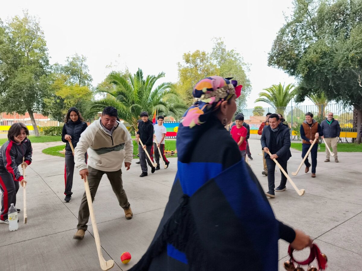 Estudiantes, docentes y directivos participando en el tradicional juego del Palín durante la conmemoración del We Tripantu.