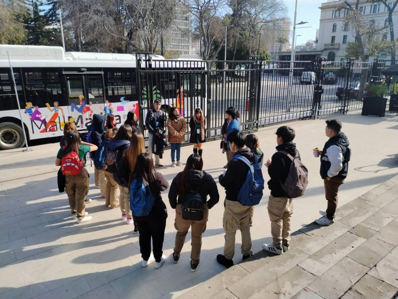 Grupo de jóvenes reunidos en el exterior junto al bus eléctrico de turismo en Viña del Mar.