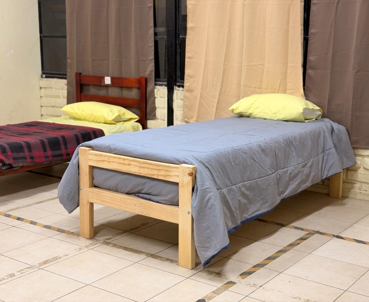 Dormitorio habilitado con camas y ropa de abrigo en el albergue de la ex Escuela Limachito.