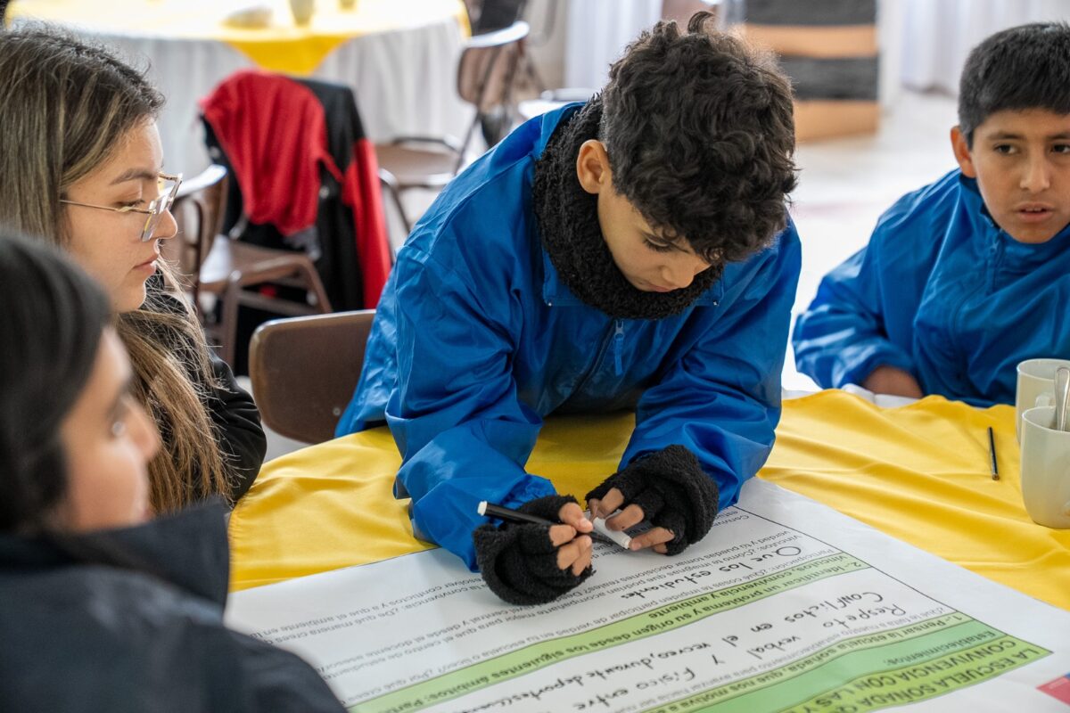Estudiante escribe propuestas en un papelógrafo durante el taller de reflexión activa.