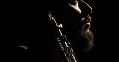 Retrato de perfil en penumbra del músico Gerardo Saks con su saxofón.