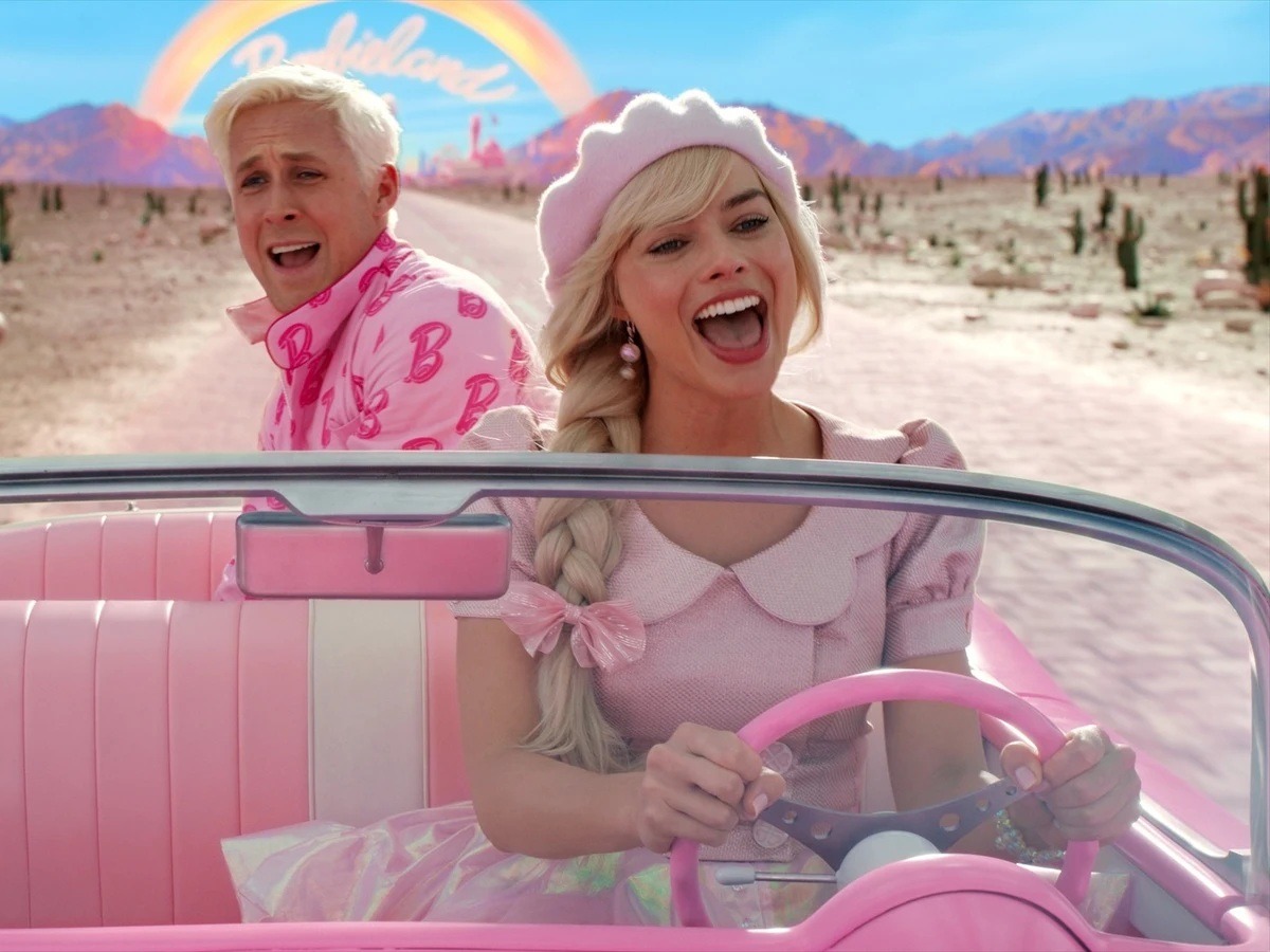 Margot Robbie como Barbie conversando con Ken en la playa de Barbieland.