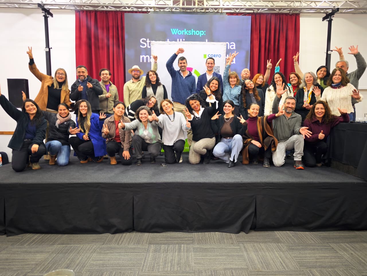 Grupo de agricultores sonriendo y posando en un escenario tras participar en un taller de branding.