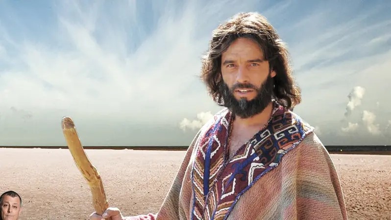 Moisés, personaje de la serie Moisés y los 10 Mandamientos, con un bastón en un desierto.