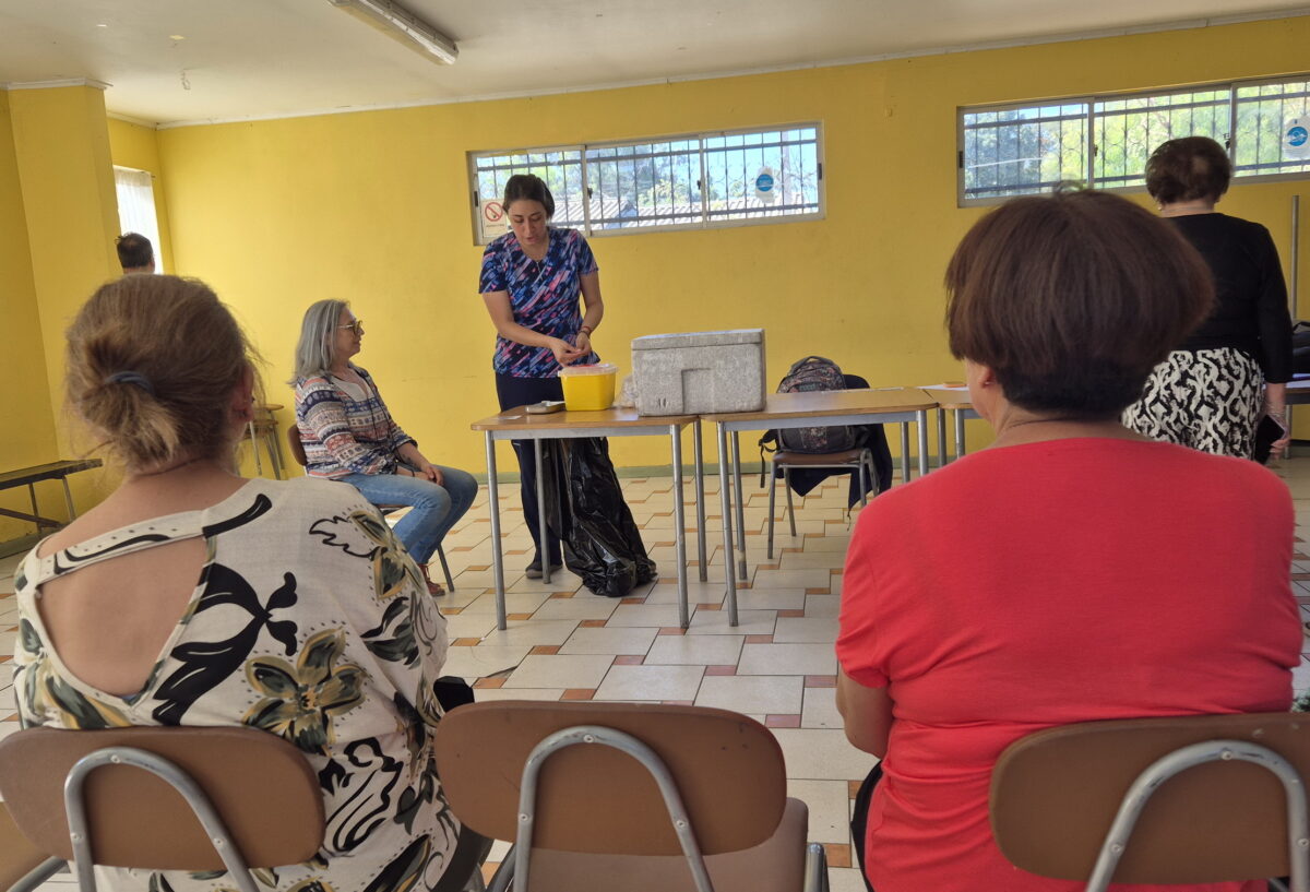 Una enfermera de SaludQuillota explicando el proceso de vacunación a un grupo de personas en una sala.