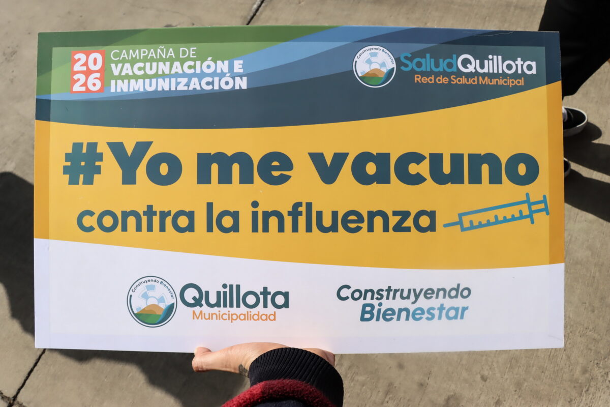 Una enfermera de SaludQuillota aplicando la vacuna contra la influenza a una mujer.