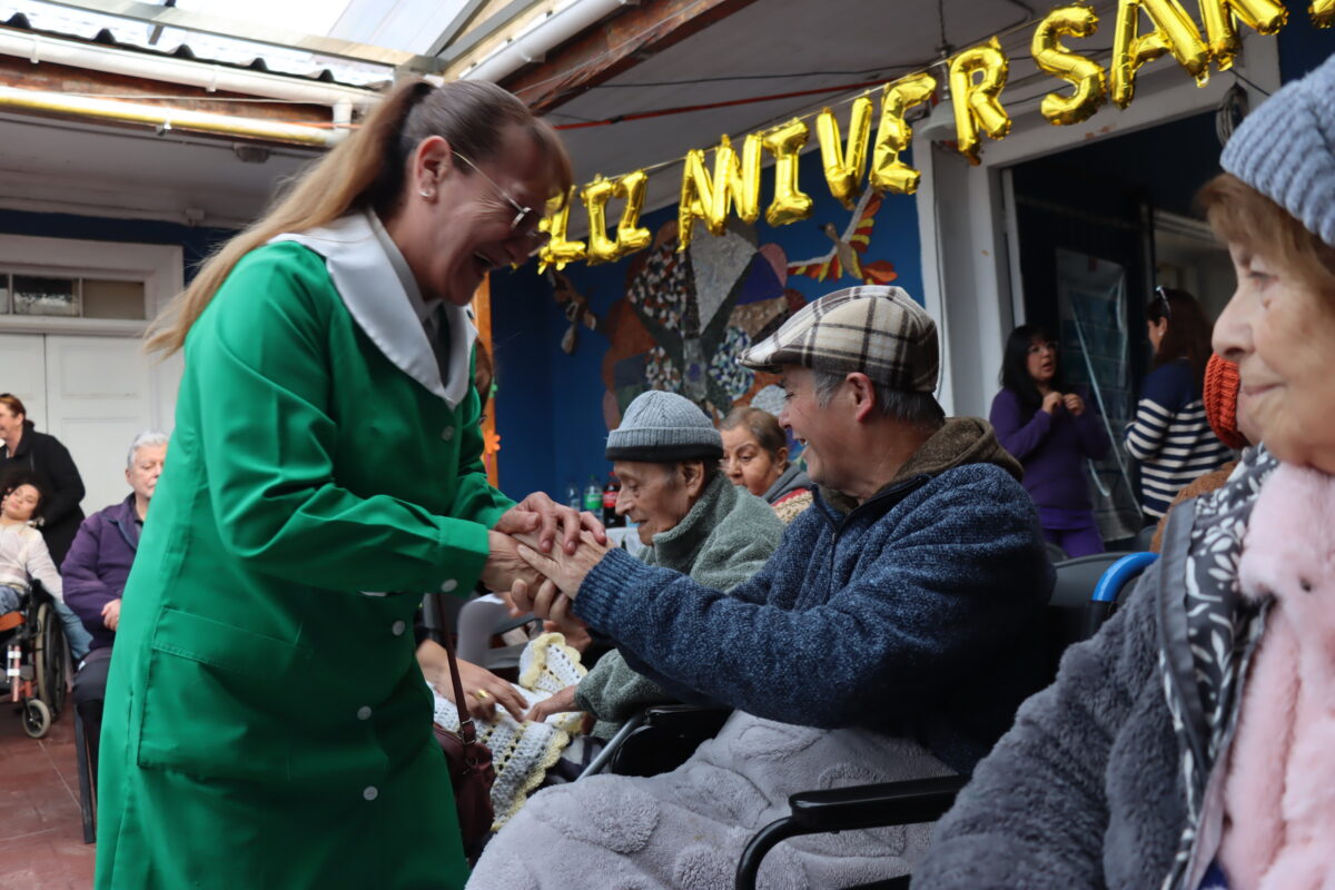 Integrante de las Damas de Verde saludando afectuosamente a un paciente mayor en la Casa de Acogida.