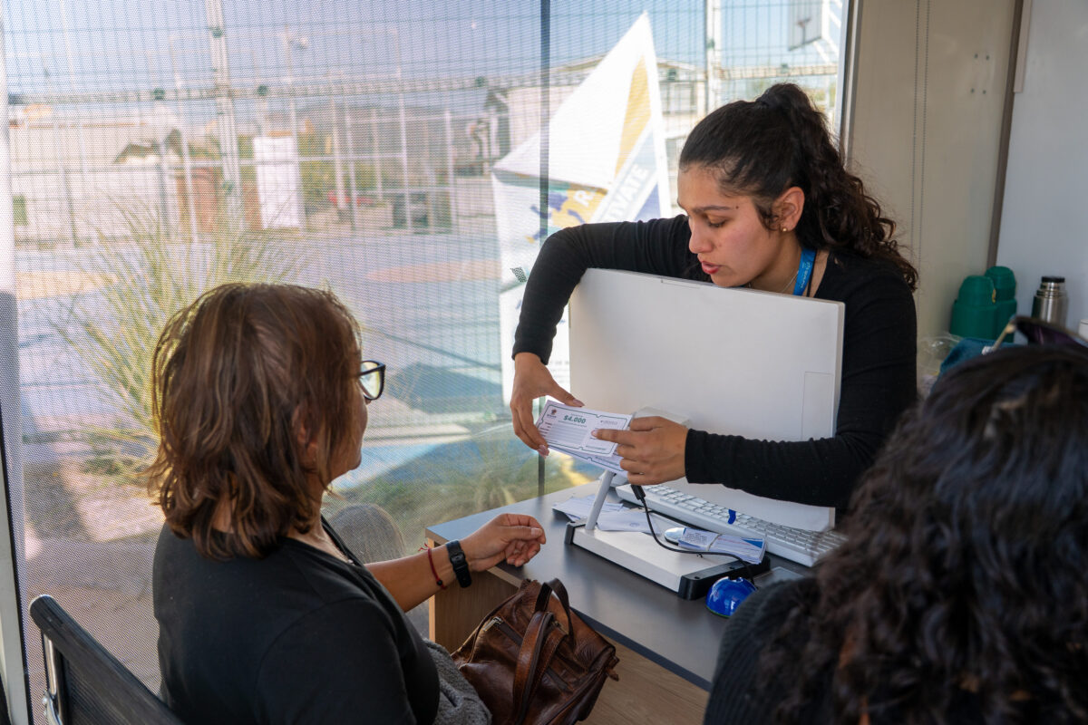 Funcionaria municipal entregando información sobre beneficios en el servicio social móvil.