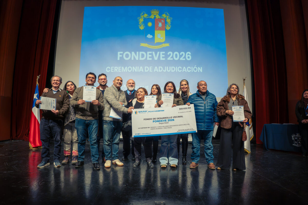 Autoridades y dirigentes vecinales de Quilpué sostienen un cheque simbólico del Fondo de Desarrollo Vecinal FONDEVE 2026 en el escenario del Teatro Municipal.