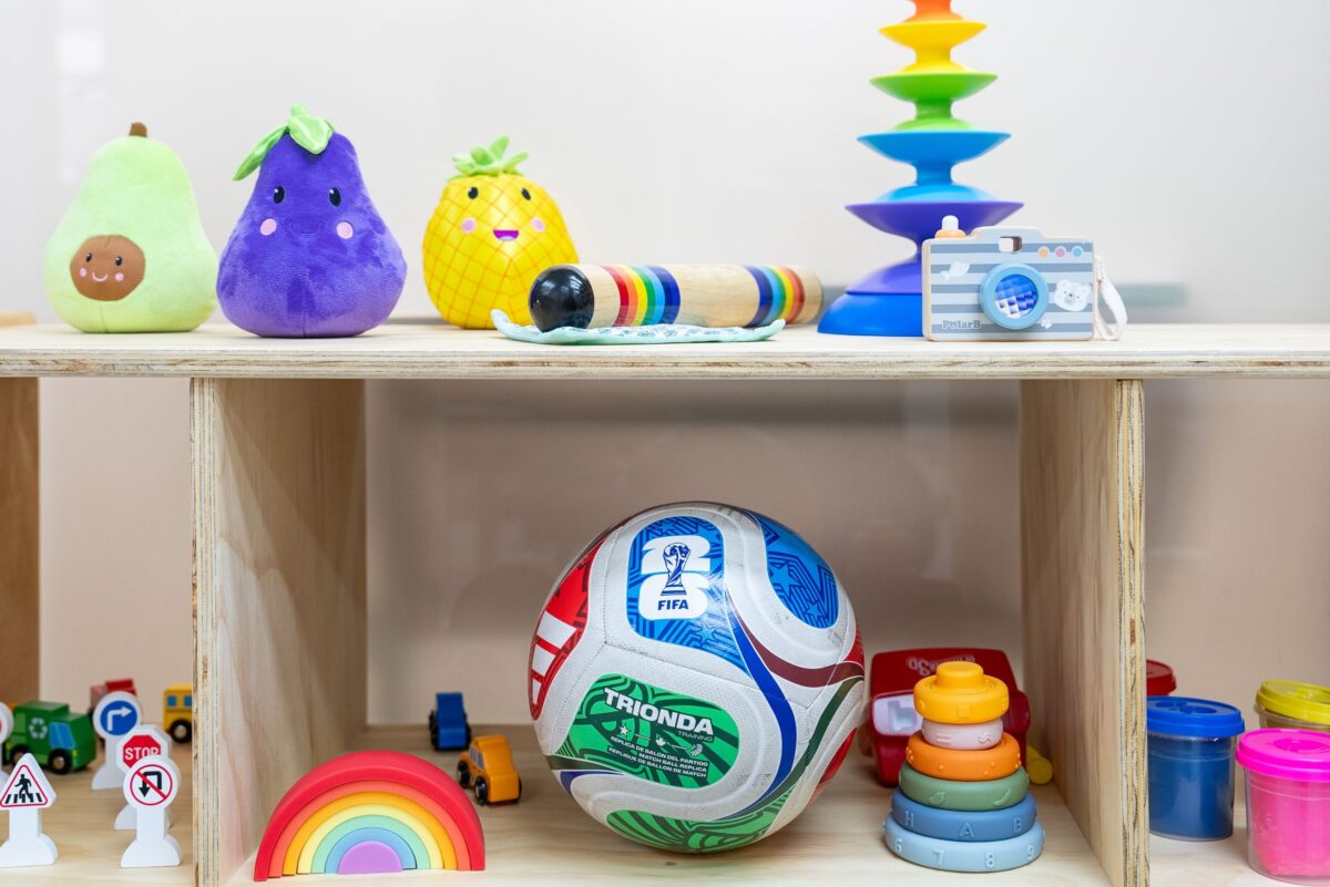 Juguetes educativos y un balón de fútbol dispuestos en un estante infantil.