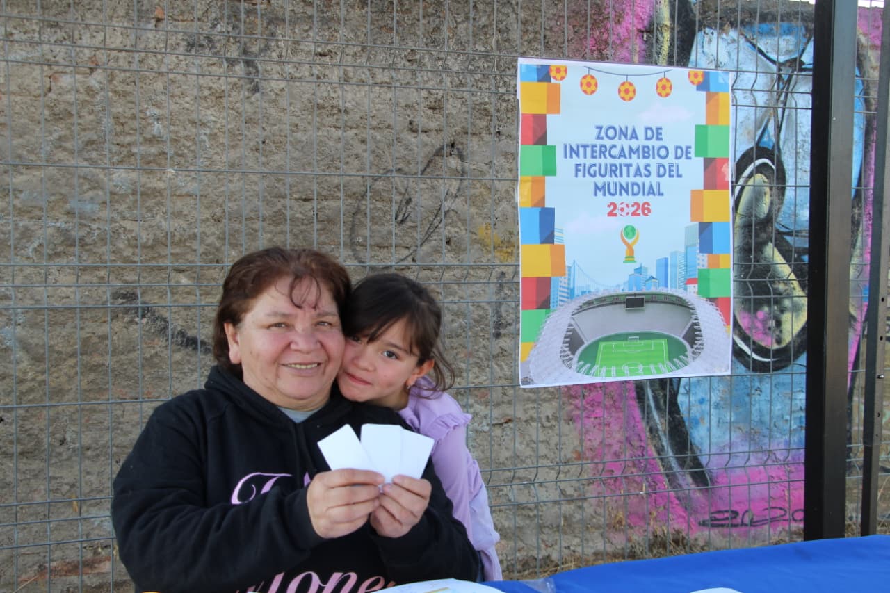 Vecina y niña sosteniendo tarjetas informativas en la zona de intercambio de la actividad.