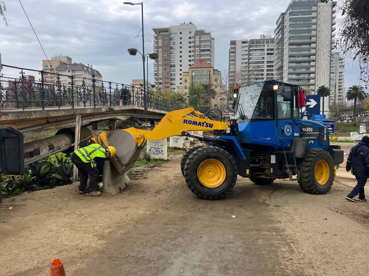 Trabajadores municipales operando maquinaria pesada en el cauce del estero.