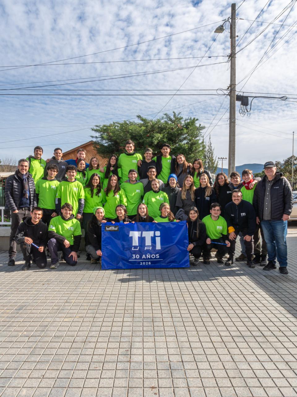 Voluntarios de la Universidad Adolfo Ibáñez posan con un lienzo conmemorativo de los 30 años de los Trabajos de Invierno en Quillota.