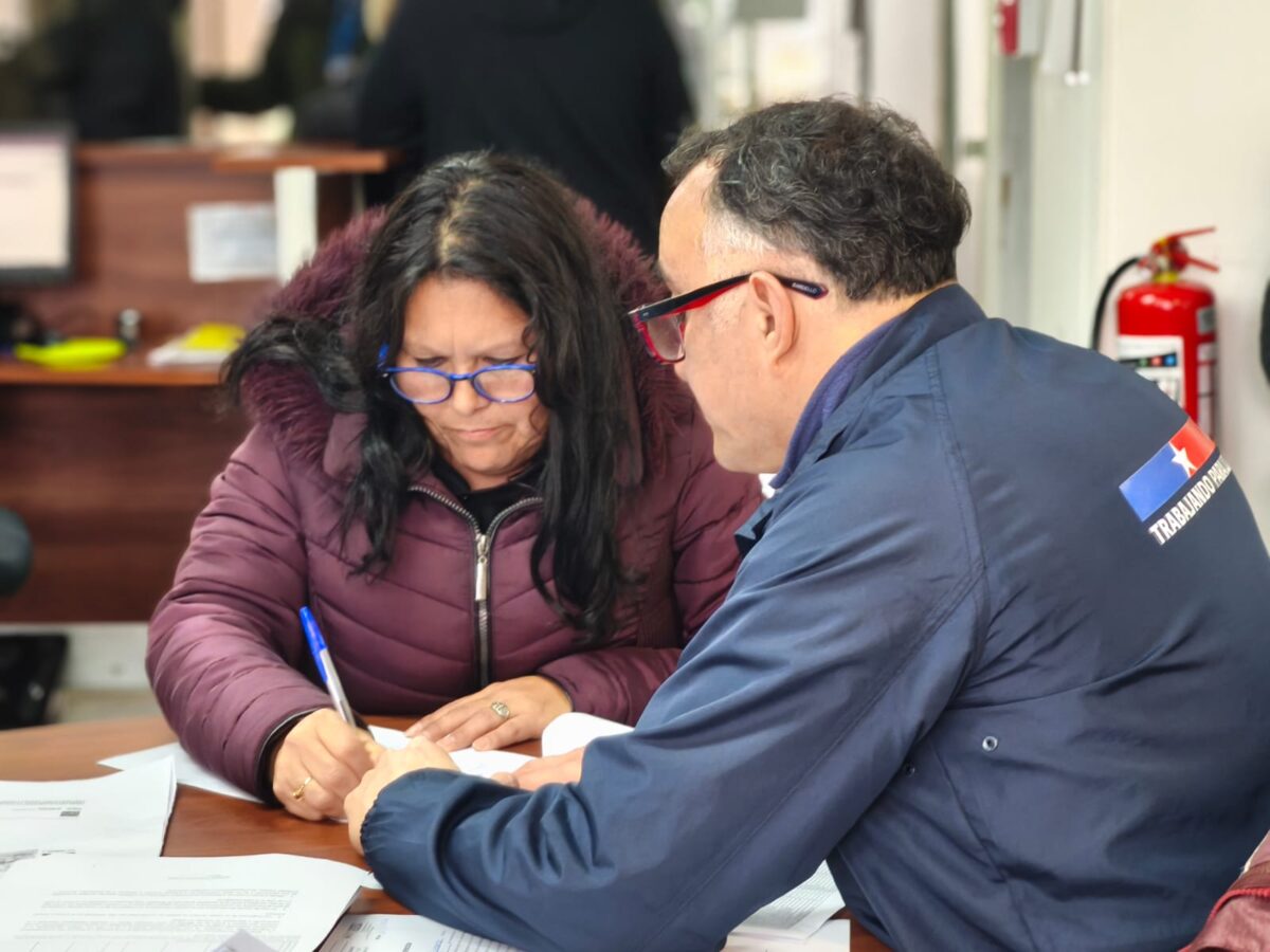 Vecina firma los documentos para obtener su título de dominio.