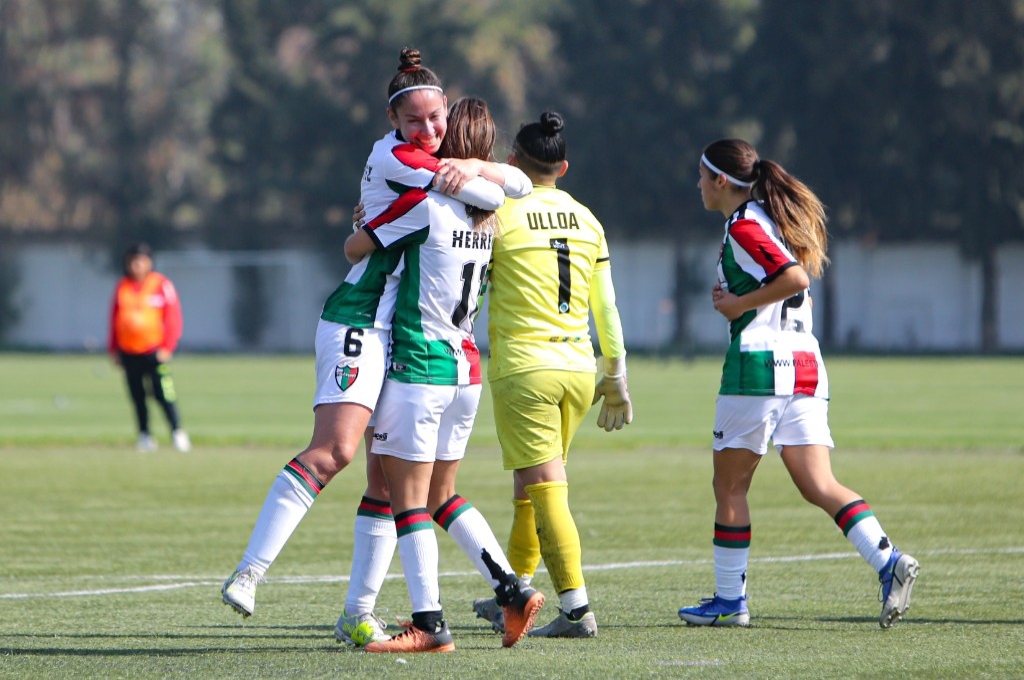 Jugadoras de fútbol celebrando un gol en el campo de juego.