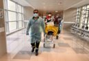 Personal de salud trasladando a un paciente simulado en camilla durante el ejercicio preparatorio.
