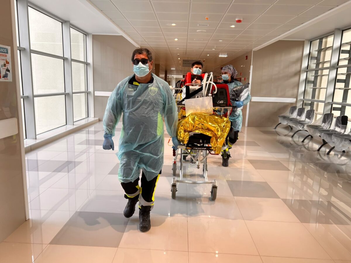 Personal de salud trasladando a un paciente simulado en camilla durante el ejercicio preparatorio.
