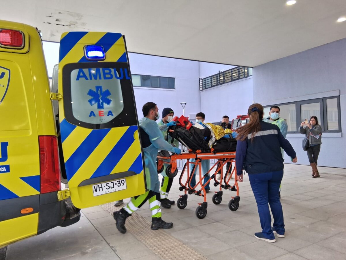 Equipo médico trasladando a un paciente en camilla hacia la ambulancia.