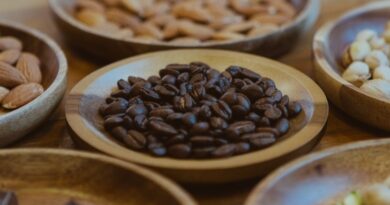 Selección de granos de café y frutos secos en recipientes de madera.