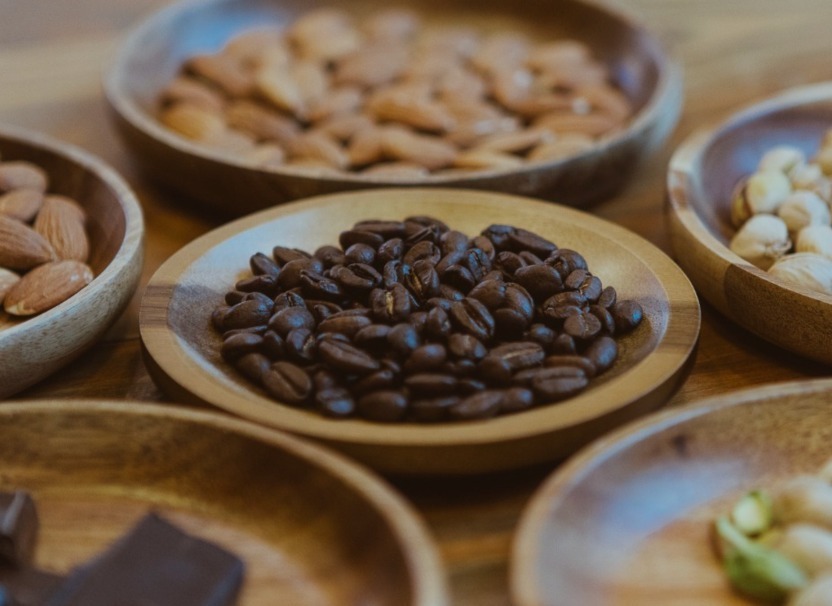 Selección de granos de café y frutos secos en recipientes de madera.