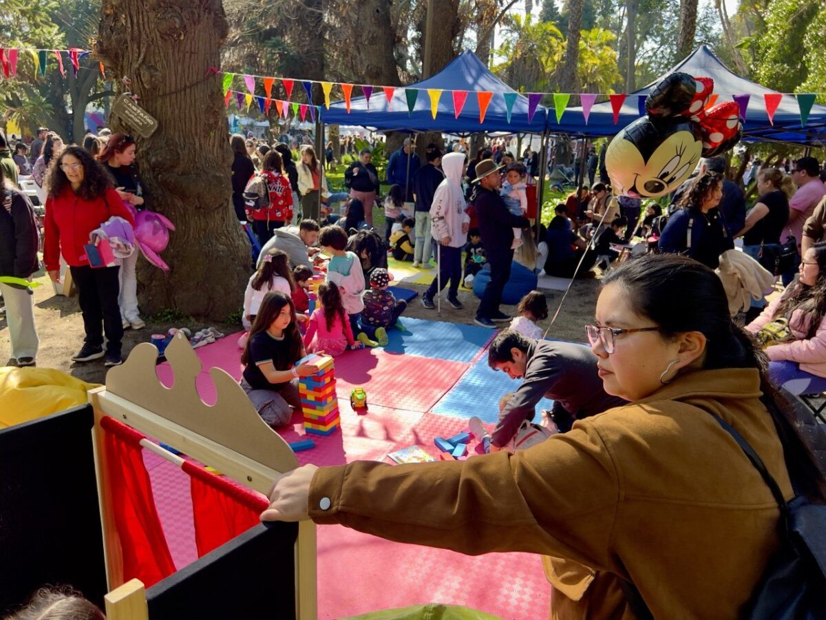 Familias disfrutando de talleres y juegos en el parque durante la celebración.