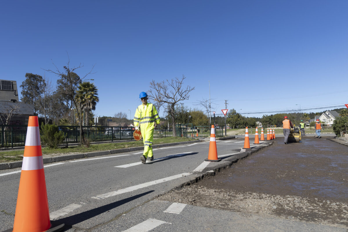 Operario de seguridad vial guiando el tránsito en zona de obras.